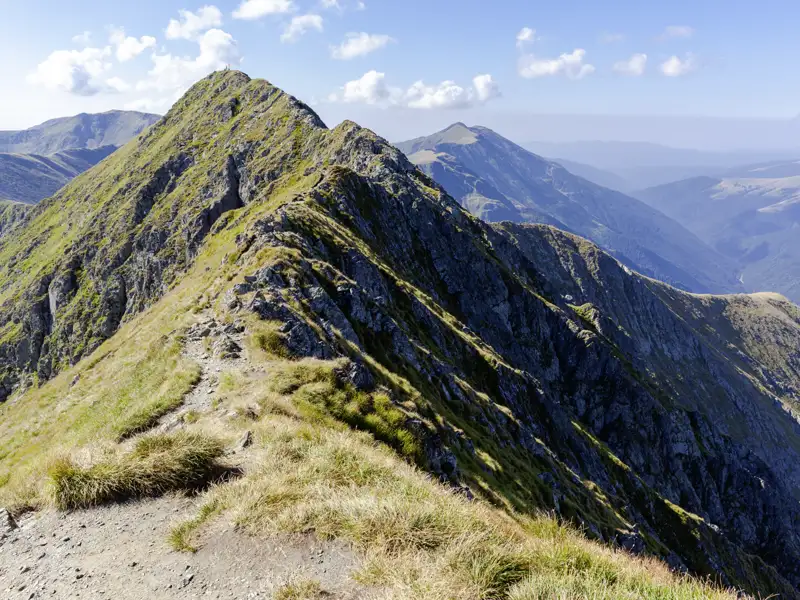 Wanderweg in den Südkarpaten auf einem Berggrat mit Blick auf weitere Berge.