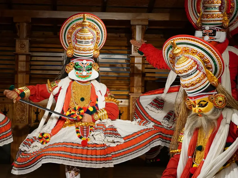 Aufführung eines Kathakali-Tanzes in Kochi bei dem die Tänzer in bunte Kostüme mit verzierten Masken gekleidet sind.