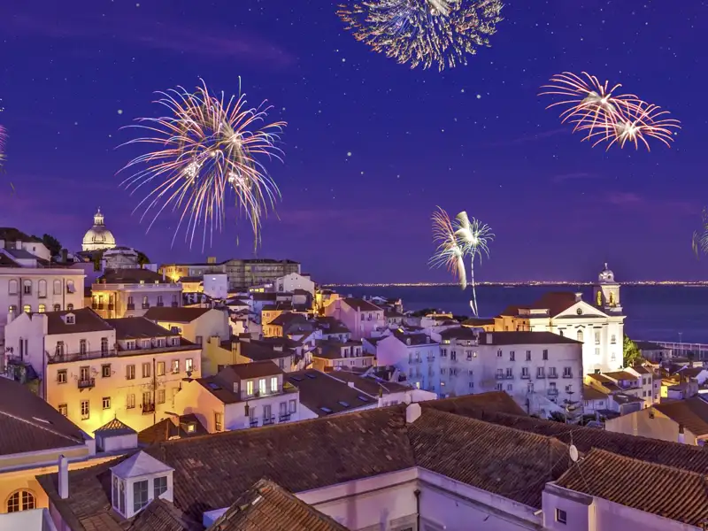 Ein buntes Silvester-Feuerwerk erhellt den Nachthimmel über der historischen Altstadt Alfama in Lissabon am Fluss Tejo.
