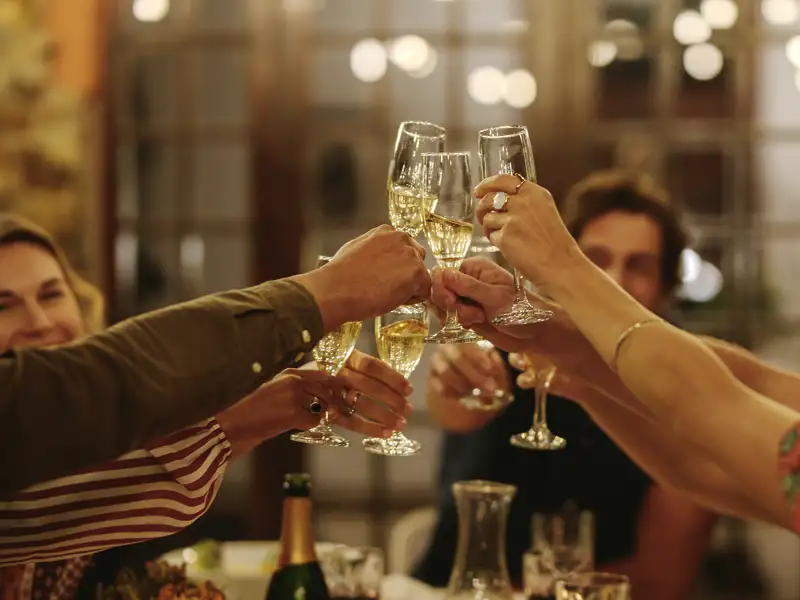 Eine Reisegruppe feiert Silvester in einer Taverne in Athen und stößt gemeinsam mit Sektgläsern auf das neue Jahr an.