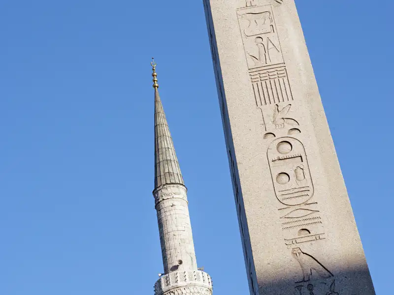 Nahaufnahme des Ägyptischen Obelisken mit Hieroglyphen neben dem Minarett der Blauen Moschee auf dem Sultanahmet-Platz in Istanbul.
