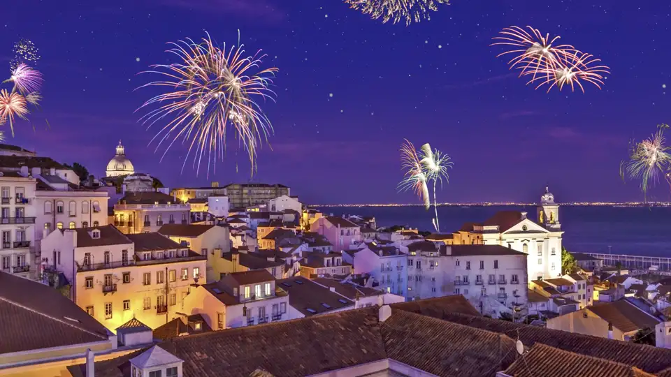 Ein buntes Silvester-Feuerwerk erhellt den Nachthimmel über der historischen Altstadt Alfama in Lissabon am Fluss Tejo.