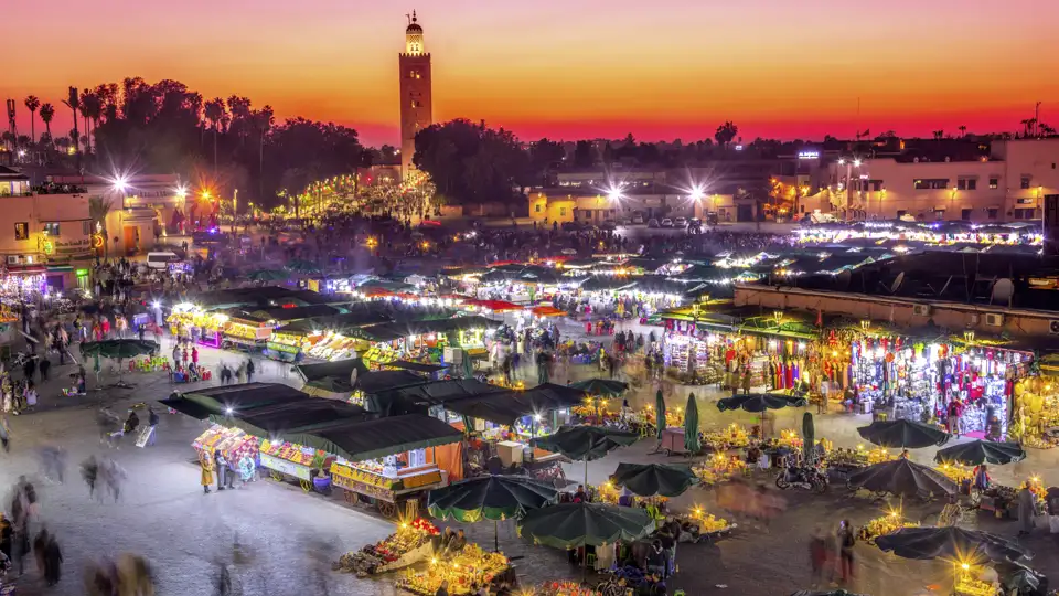 Der Djemaa el-Fna bei Abendrot mit vielen beleuchteten Marktständen. Früher mal Platz der Gehenkten, heute tobt das Leben auf dem zentralen Marktplatz in Marrakesch.